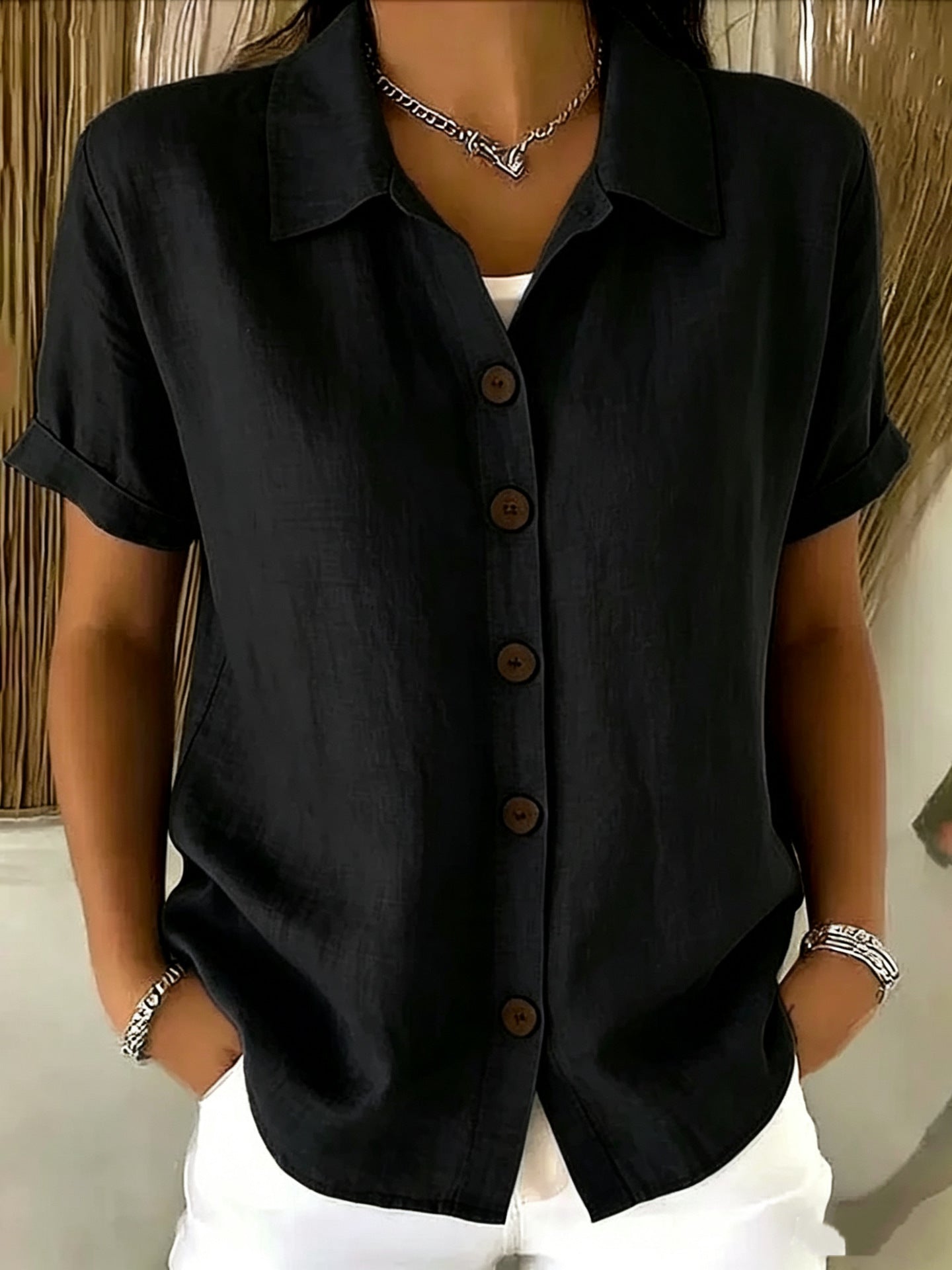 Women's collared button-front shirt in black with short sleeves and dark buttons.