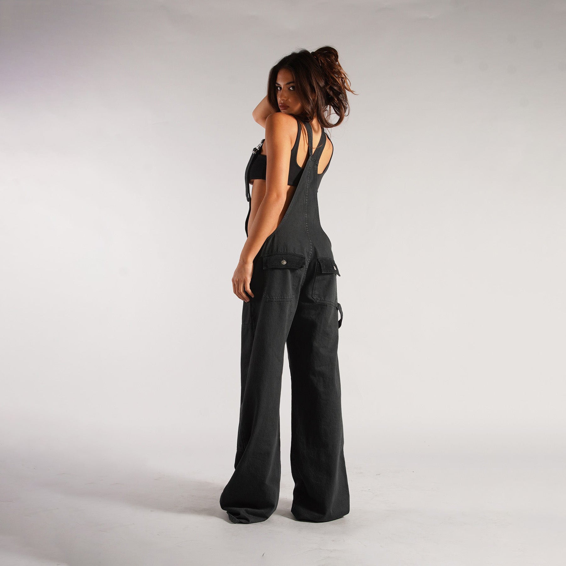 Black denim zipper overalls side view with suspender straps, wide legs, patch pockets