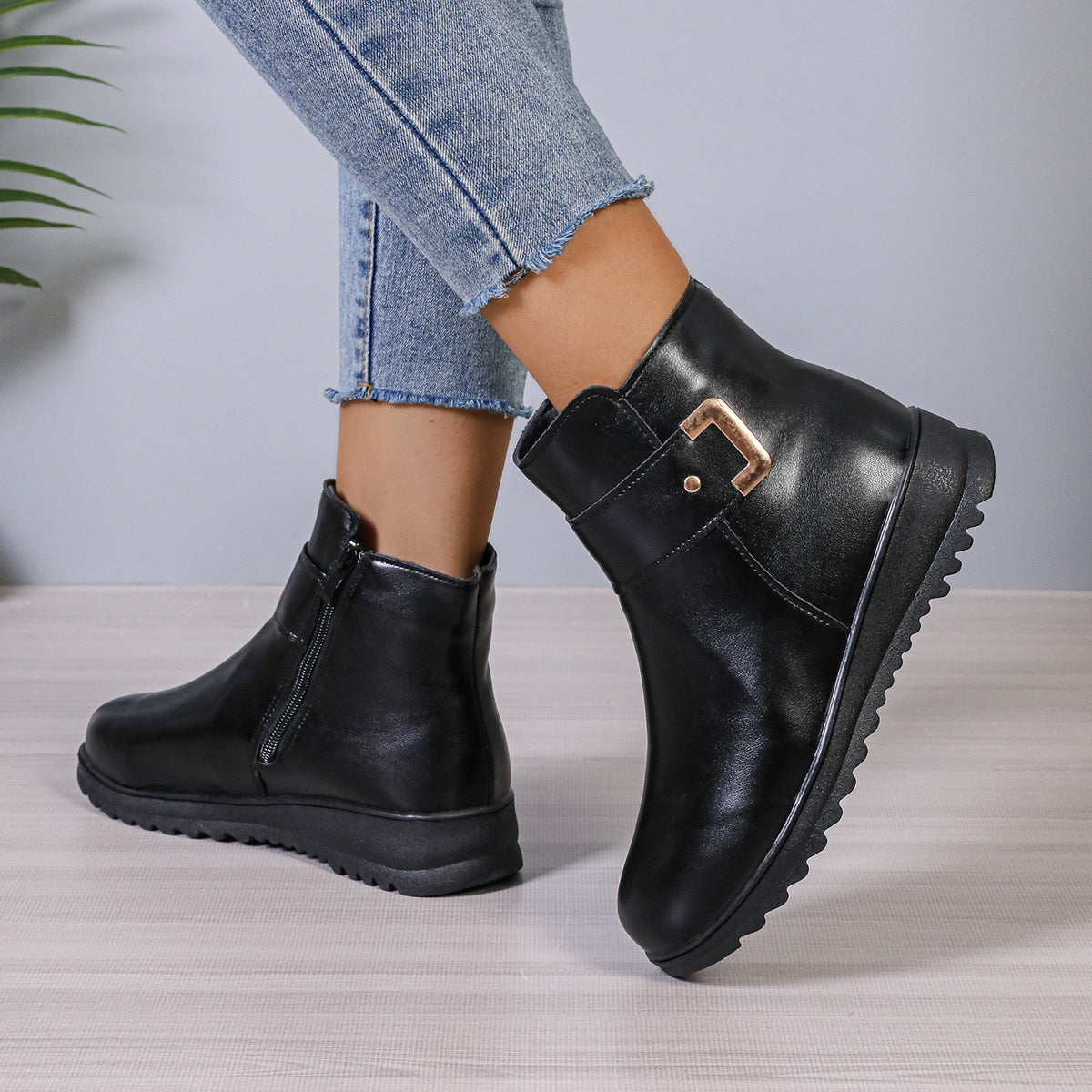 Women’s black ankle boots with buckle strap detail and chunky tread sole