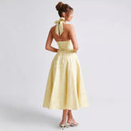 Light yellow sleeveless long dress shown from back with open V halter and waist tie