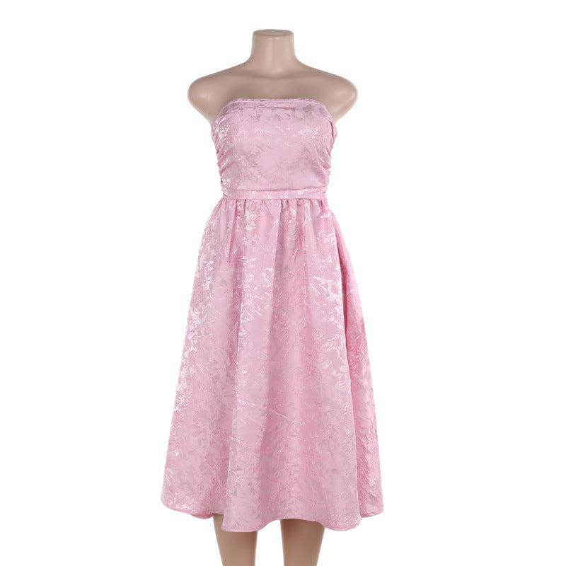 Pink satin jacquard tube top dress on mannequin with gathered waist and flared skirt.