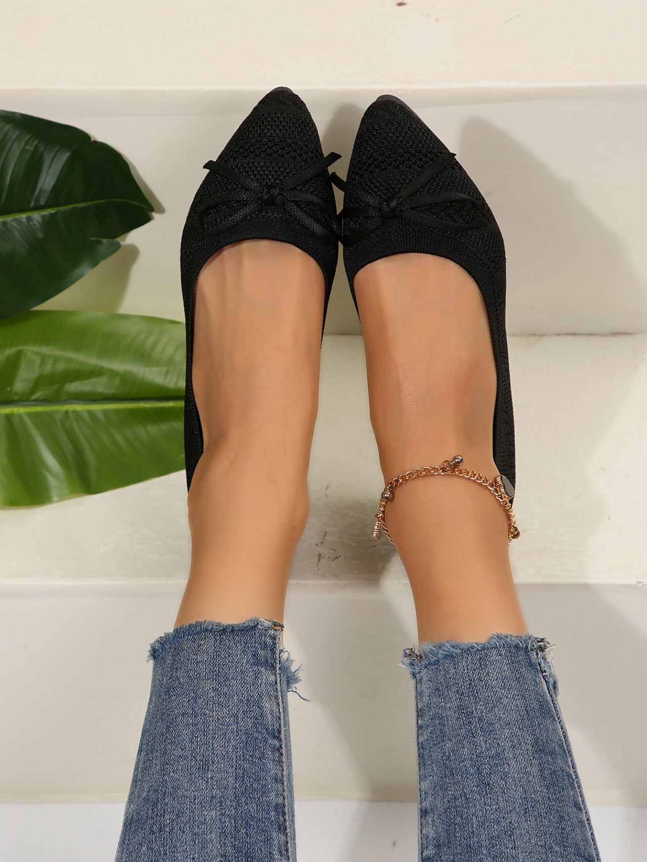 Black knit pointed-toe loafers with bow and gold beaded ankle chain