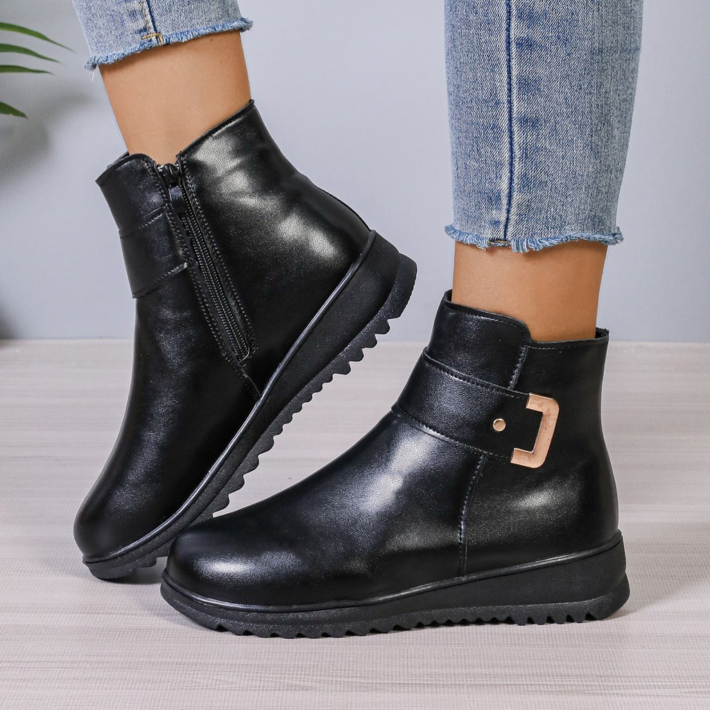 Women’s black ankle boots with side zipper, buckle hardware, and grippy sole