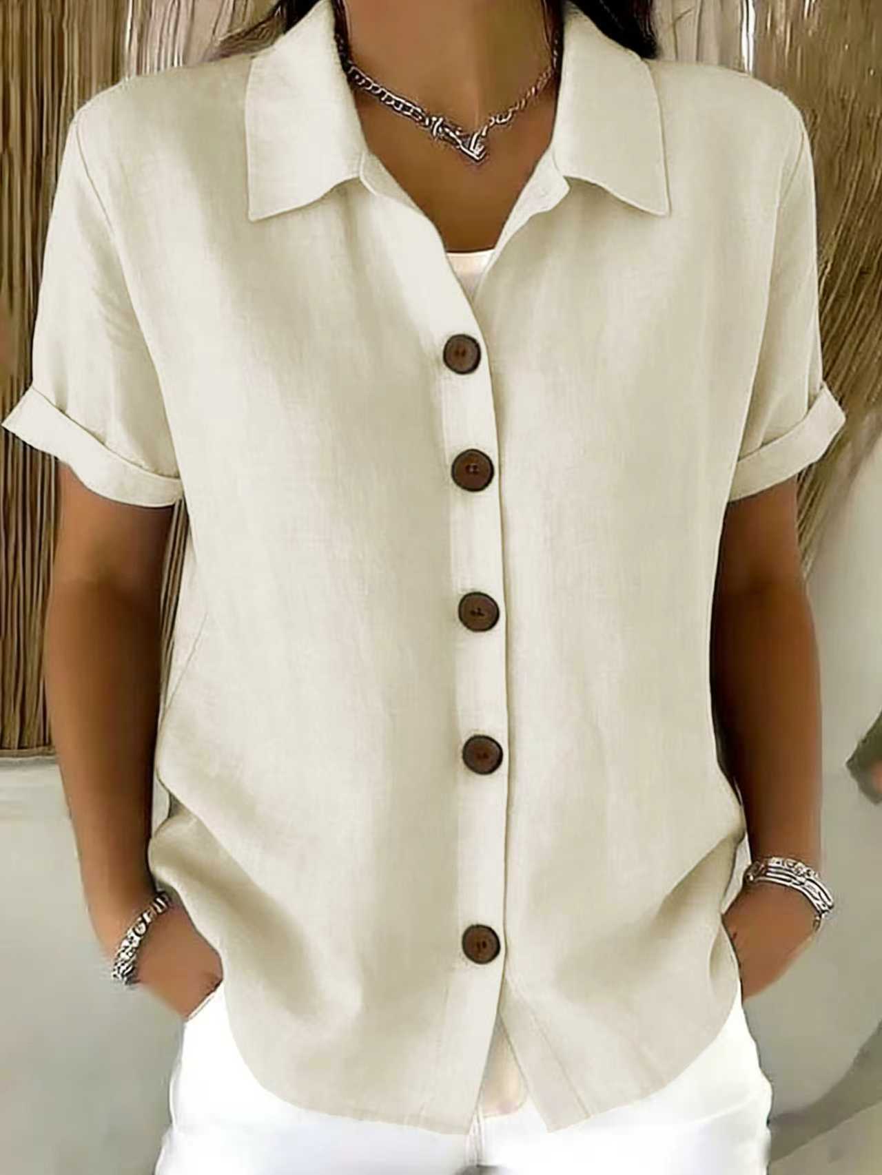Women's collared button-front shirt in off-white with short sleeves and dark buttons.