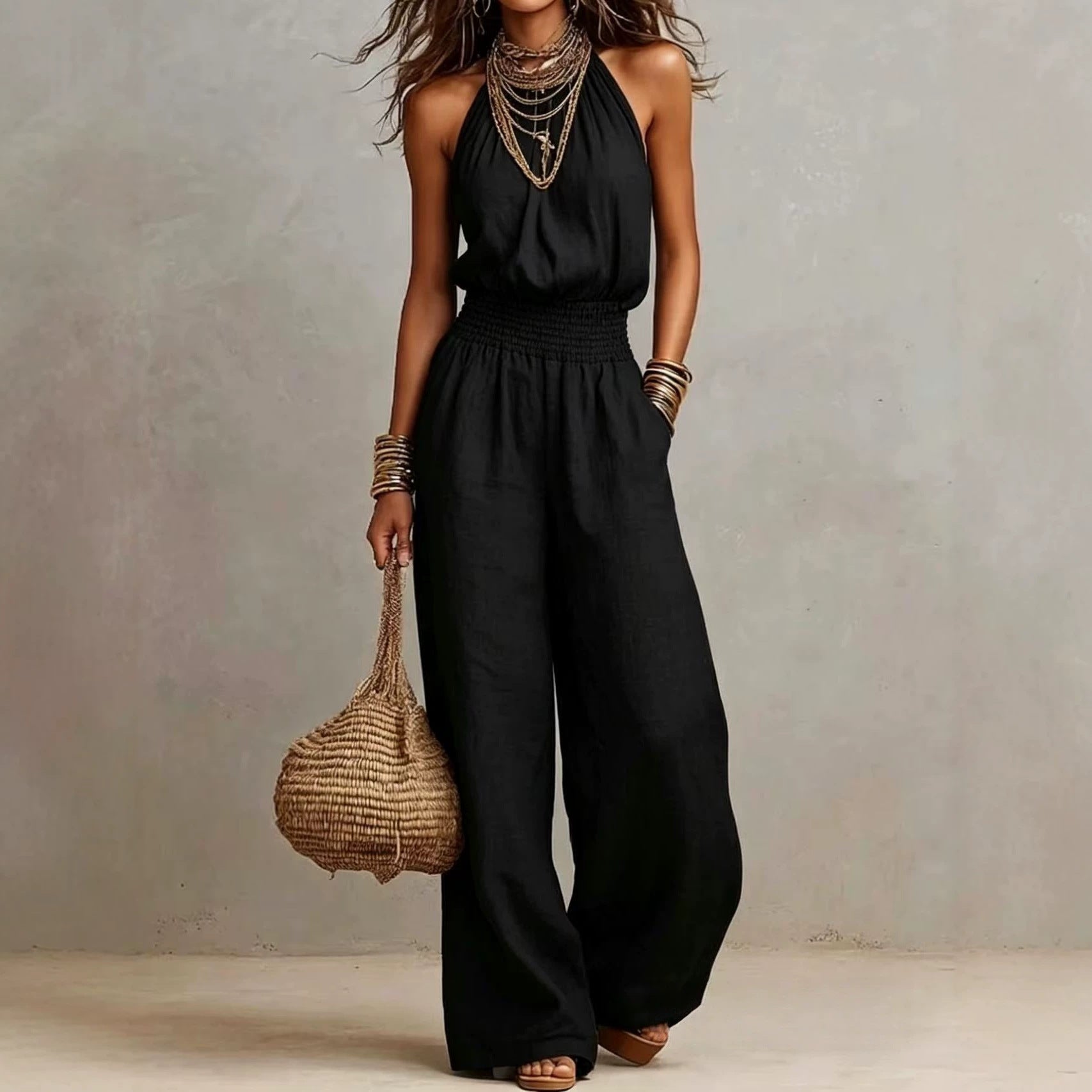 Black sleeveless jumpsuit with halter neck, smocked waist, and wide legs